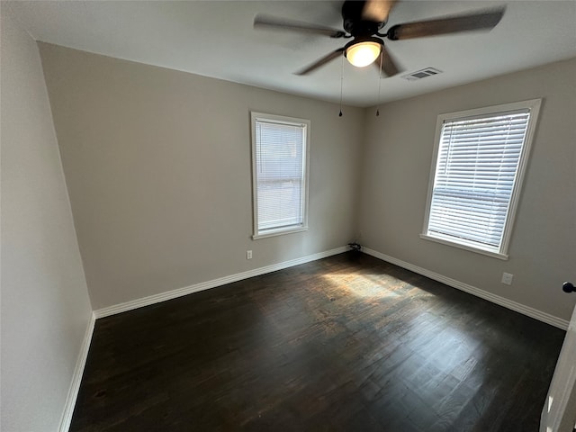 empty room with ceiling fan, plenty of natural light, and dark hardwood / wood-style flooring