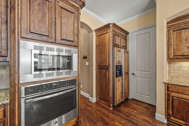 kitchen with light stone counters, dark hardwood / wood-style flooring, crown molding, decorative backsplash, and appliances with stainless steel finishes