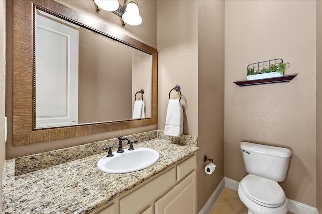 bathroom with toilet, vanity, and tile patterned floors