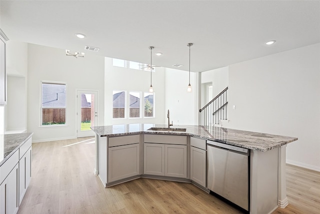 kitchen with stainless steel dishwasher, light hardwood / wood-style flooring, light stone counters, and tasteful backsplash