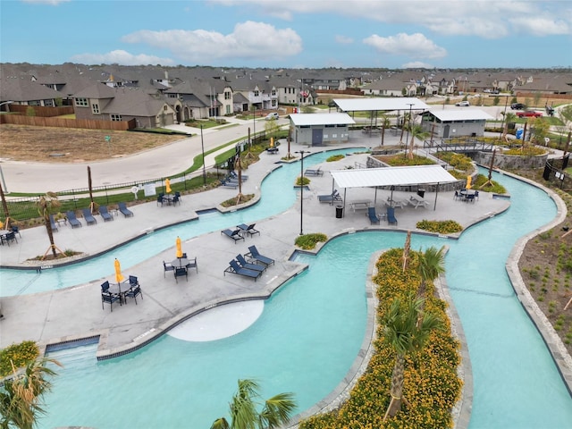 community pool with a residential view, a patio area, and fence