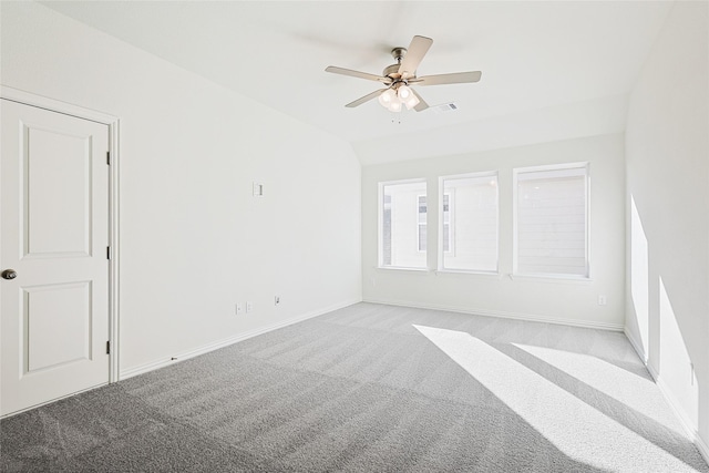 spare room featuring light carpet, visible vents, a ceiling fan, vaulted ceiling, and baseboards