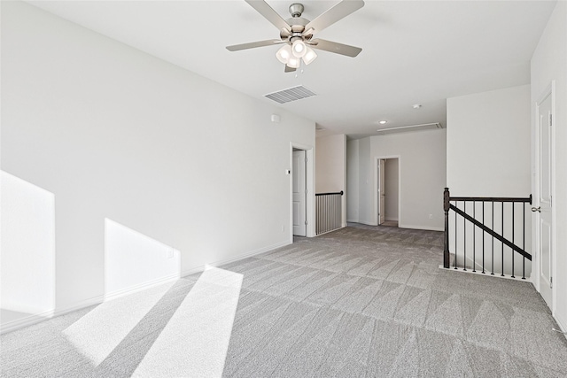 empty room with light carpet, a ceiling fan, visible vents, and baseboards