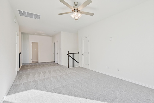 empty room with baseboards, visible vents, a ceiling fan, and light colored carpet