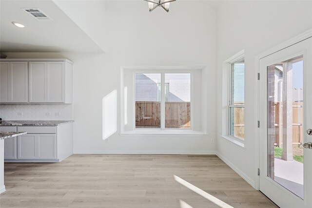 kitchen with hanging light fixtures, light stone counters, appliances with stainless steel finishes, light wood-type flooring, and sink