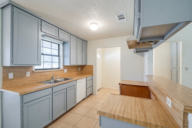 kitchen with light tile patterned floors, white dishwasher, sink, decorative backsplash, and a textured ceiling