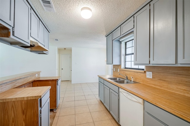 kitchen featuring visible vents, dishwasher, gray cabinets, a sink, and light tile patterned flooring