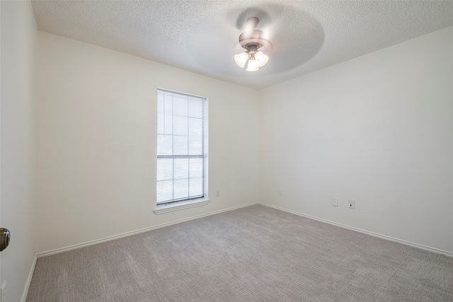 unfurnished room with ceiling fan, light carpet, and a textured ceiling