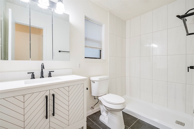 bathroom with toilet, tile patterned floors, vanity, a textured ceiling, and tiled shower