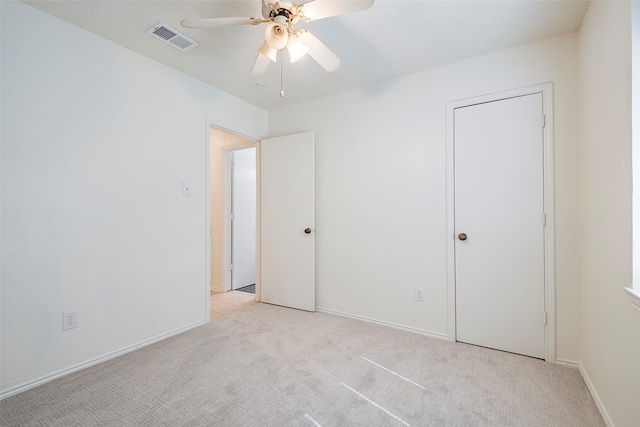 unfurnished bedroom featuring a ceiling fan, light colored carpet, visible vents, and baseboards