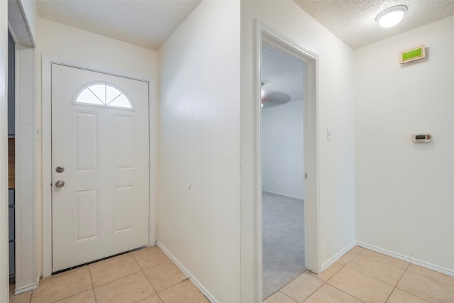 carpeted foyer with a textured ceiling