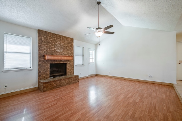 unfurnished living room with plenty of natural light, vaulted ceiling, a brick fireplace, and ceiling fan