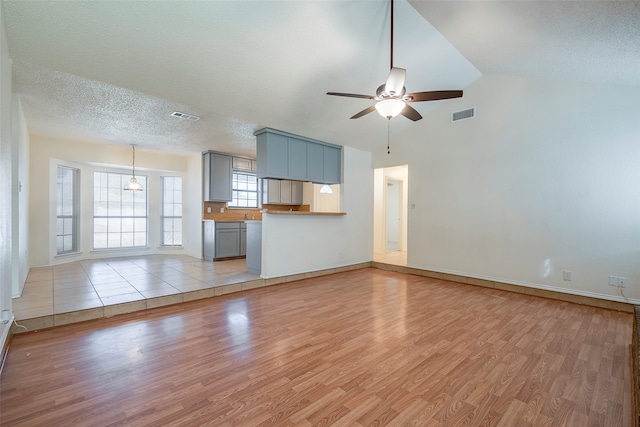 unfurnished living room featuring a textured ceiling, light hardwood / wood-style flooring, ceiling fan, and vaulted ceiling