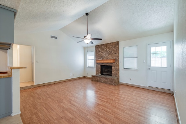 unfurnished living room with light wood-type flooring, ceiling fan, lofted ceiling, and a brick fireplace