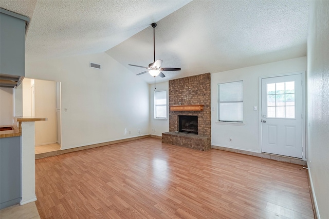 unfurnished living room with a ceiling fan, light wood-type flooring, visible vents, and a fireplace