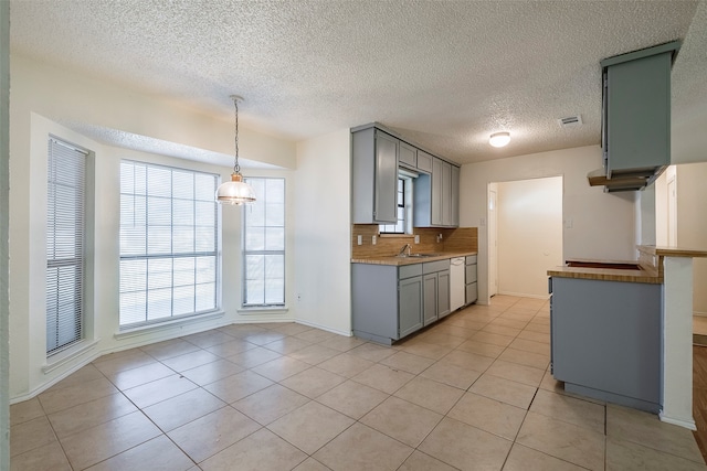 kitchen featuring a textured ceiling, white dishwasher, pendant lighting, light tile patterned floors, and tasteful backsplash