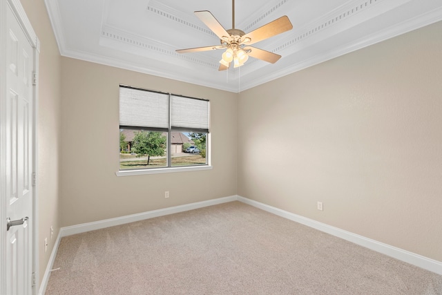 carpeted empty room featuring ceiling fan, crown molding, and a tray ceiling