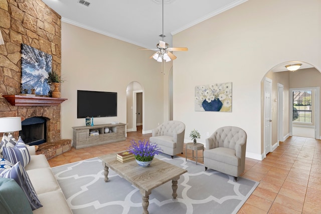 living room featuring ornamental molding, ceiling fan, light tile patterned floors, high vaulted ceiling, and a stone fireplace