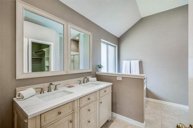 bathroom featuring vaulted ceiling, double vanity, baseboards, and a sink