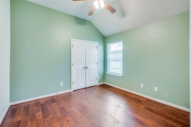 empty room with vaulted ceiling, a ceiling fan, baseboards, and wood finished floors