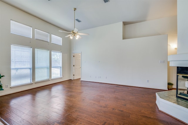 unfurnished living room featuring baseboards, visible vents, a high ceiling, ceiling fan, and dark wood-type flooring