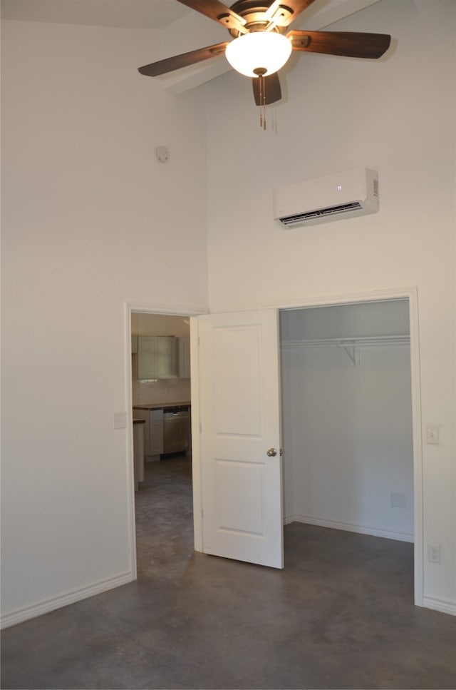 unfurnished bedroom featuring a high ceiling, a closet, ceiling fan, and a wall mounted air conditioner