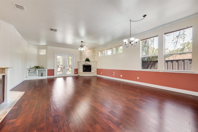 unfurnished living room featuring a fireplace, ceiling fan with notable chandelier, a wealth of natural light, and ornamental molding