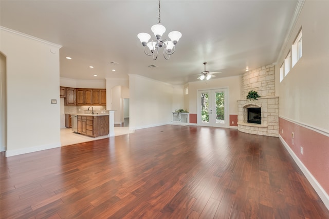 unfurnished living room featuring light hardwood / wood-style flooring, ceiling fan with notable chandelier, ornamental molding, and a stone fireplace