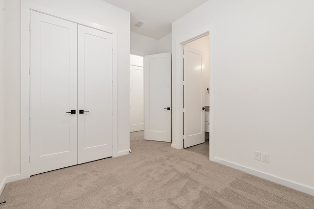 unfurnished bedroom with light colored carpet and a closet