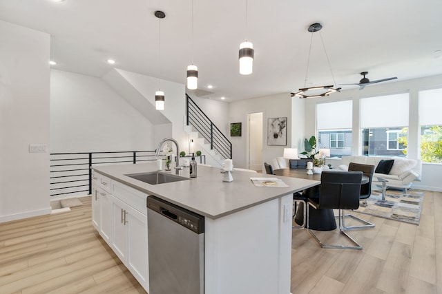 kitchen with pendant lighting, a center island with sink, stainless steel dishwasher, and sink