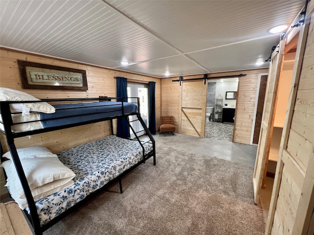 bedroom with a barn door and wood walls