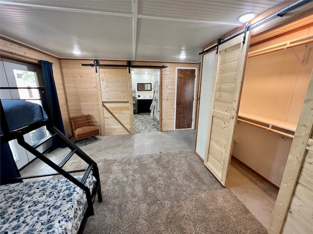 bedroom with a barn door and wood walls