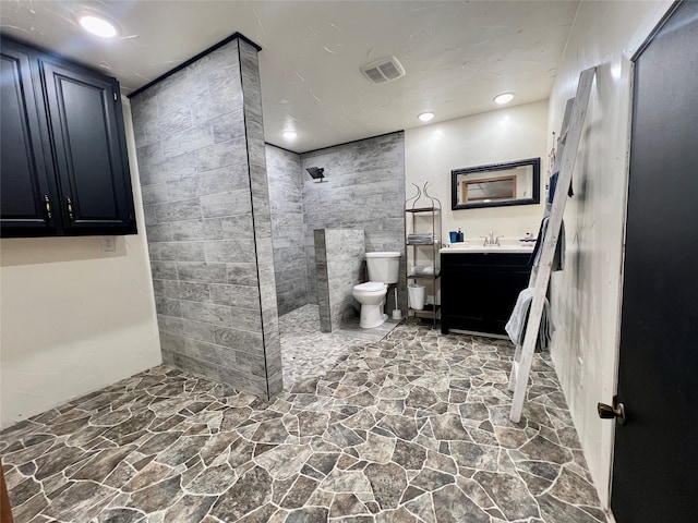 bathroom featuring vanity, toilet, a tile shower, and a textured ceiling