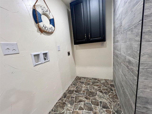 washroom featuring cabinet space, washer hookup, and stone floors