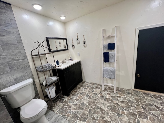 bathroom featuring tile walls, toilet, and vanity