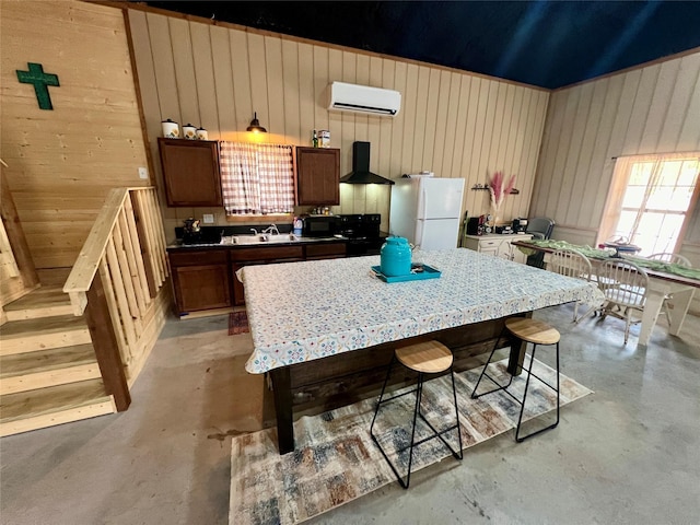 kitchen featuring concrete flooring, freestanding refrigerator, black microwave, wall chimney exhaust hood, and a wall mounted AC