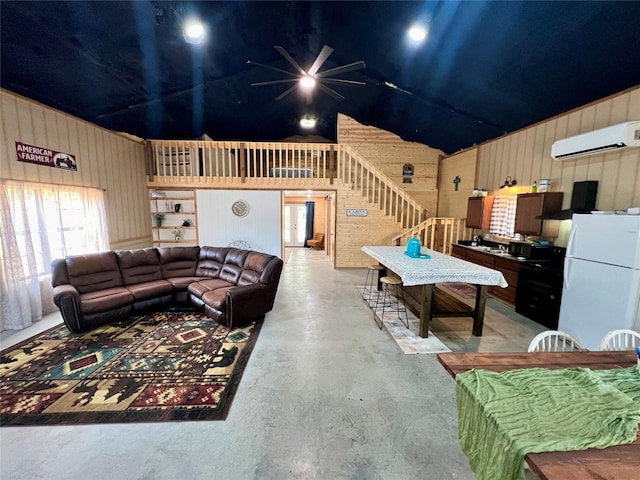 living room with wooden walls, lofted ceiling, an AC wall unit, and ceiling fan