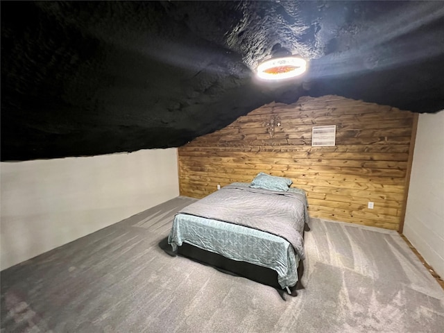 carpeted bedroom with lofted ceiling and wooden walls