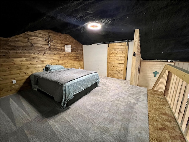 bedroom featuring a barn door, wood walls, and lofted ceiling