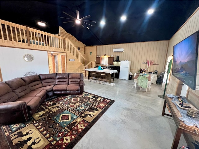 living room featuring a wall unit AC, finished concrete flooring, lofted ceiling, stairs, and wooden walls