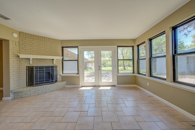 unfurnished living room featuring french doors, a brick fireplace, and light tile patterned floors