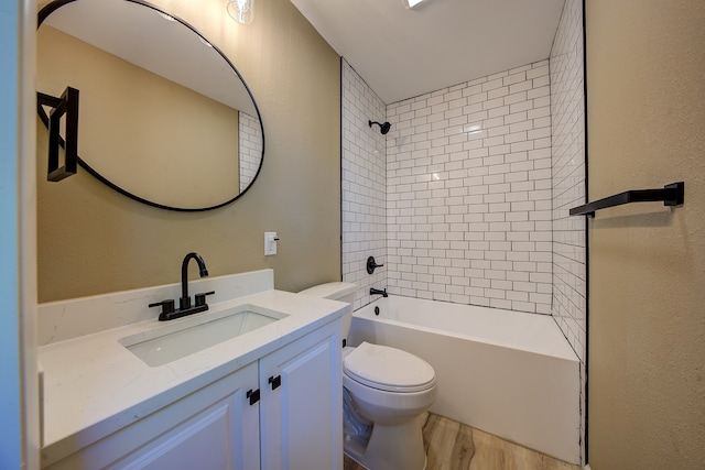 full bathroom featuring hardwood / wood-style floors, toilet, tiled shower / bath combo, and vanity