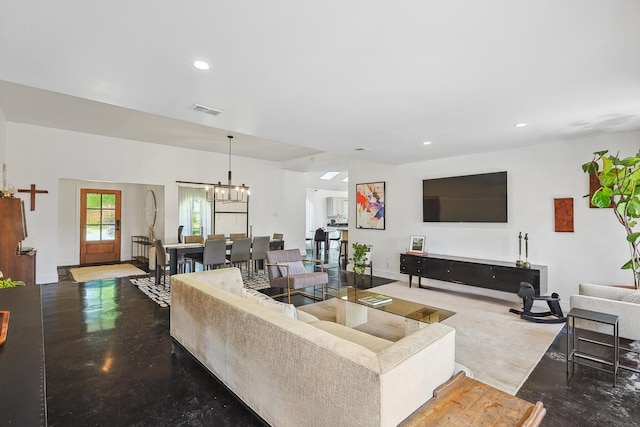 living room featuring a chandelier and concrete floors