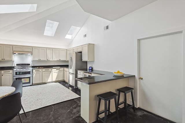 kitchen featuring a skylight, stainless steel appliances, kitchen peninsula, high vaulted ceiling, and a kitchen bar