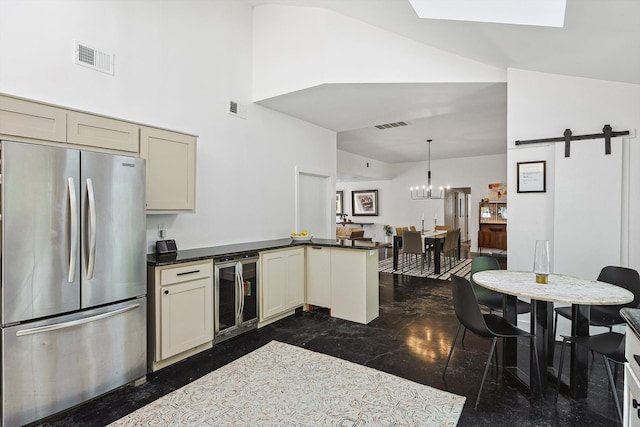 kitchen with cream cabinets, a barn door, stainless steel fridge, beverage cooler, and pendant lighting