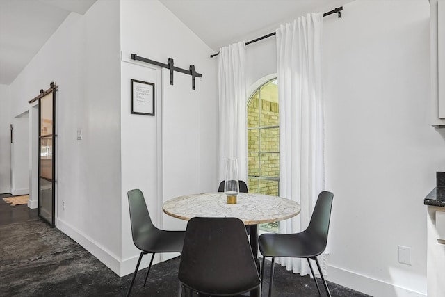 dining space featuring vaulted ceiling, concrete floors, and a barn door