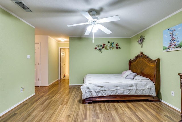 bedroom with wood finished floors, visible vents, baseboards, ceiling fan, and crown molding