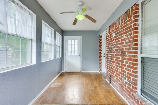 unfurnished sunroom with ceiling fan