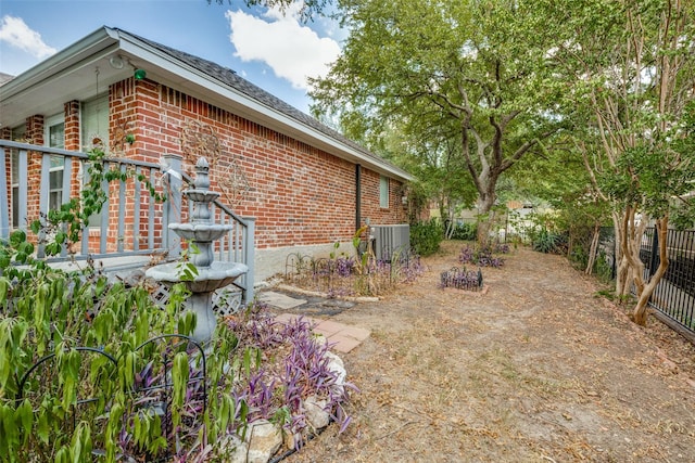 view of home's exterior with central air condition unit, fence, and brick siding