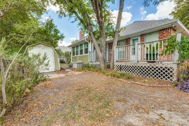 back of property with brick siding, a shed, a chimney, an outdoor structure, and a deck